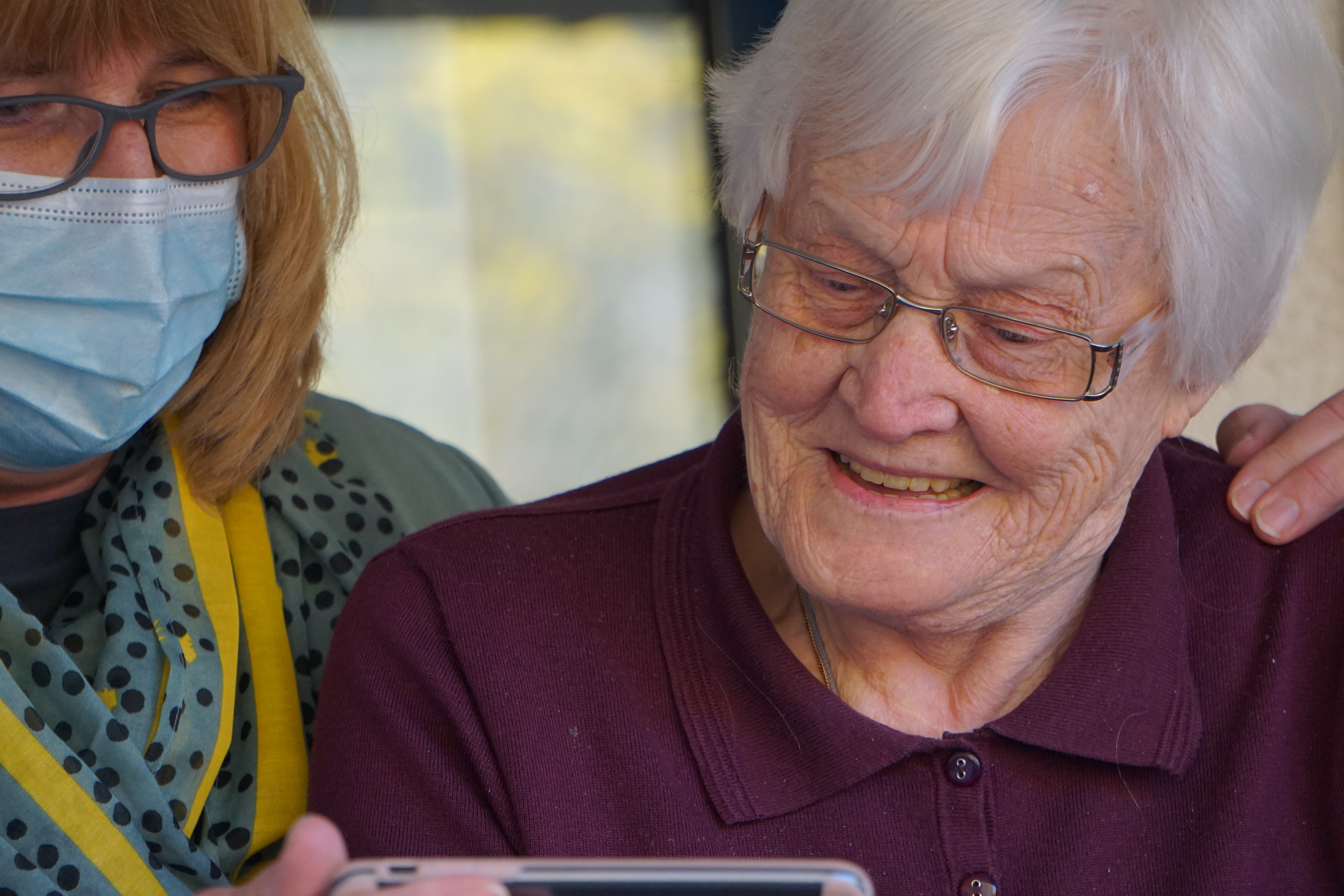 Image of a nurse and older adult looking at a phone 